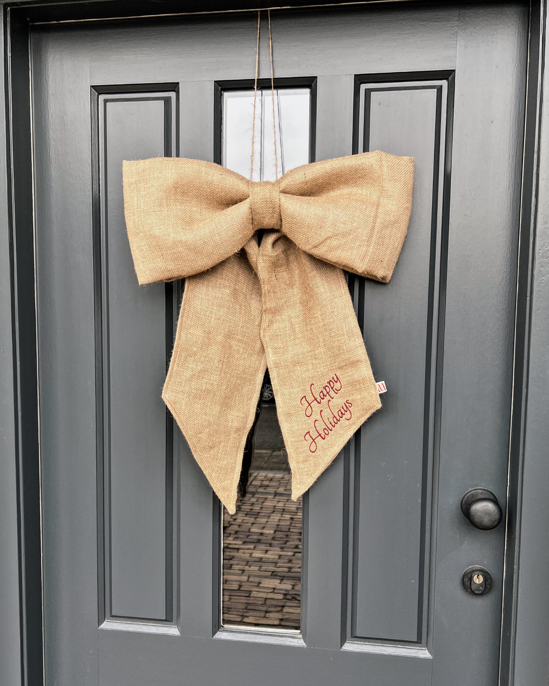 Kerststrik Jute Natural aan voordeur met festive quote geborduurd