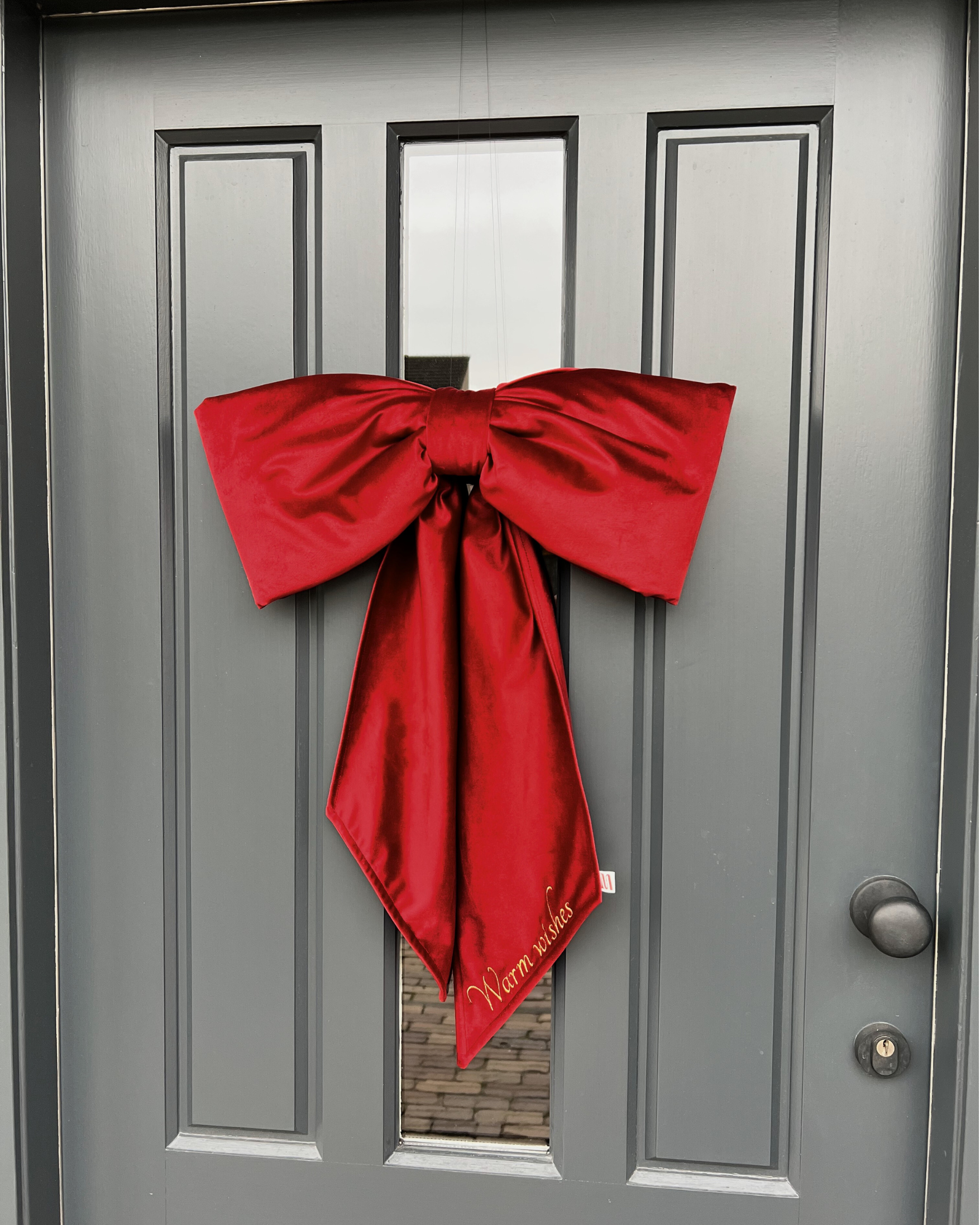 Kerststrik Red Velvet aan voordeur met festive quote geborduurd